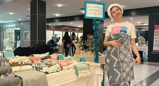 Owner of Turkish Towels Etc. showcasing Turkish towels at a festive Christmas market booth