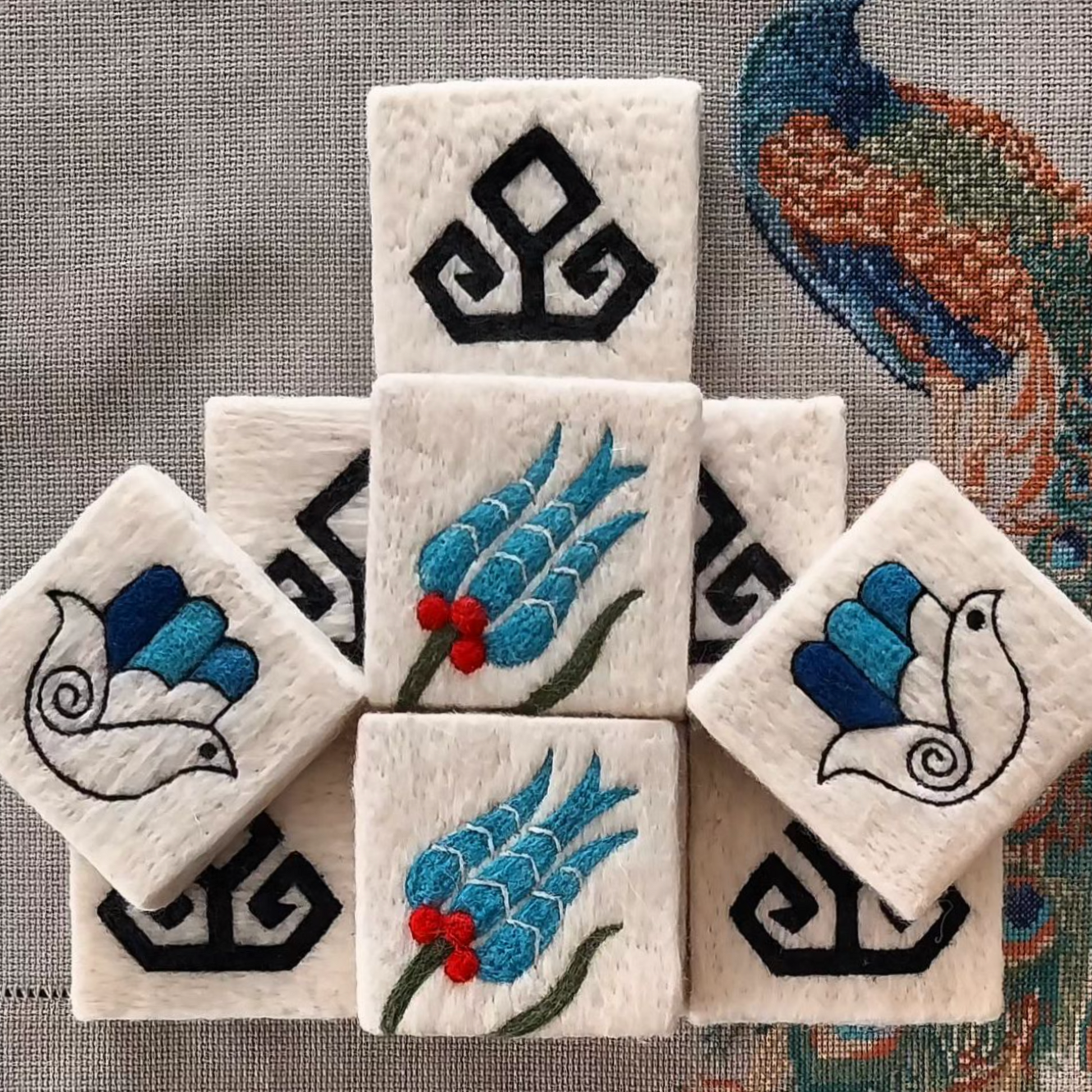 Handmade Turkish felted soap bars with traditional motifs including eli belinde, tulip, and hamsa designs, displayed on a decorative cloth