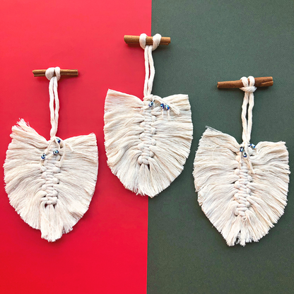 Set of 3 cream macrame feathers with cinnamon stick hangers on a festive Christmas background, ideal for adding a natural, bohemian touch to your holiday decor