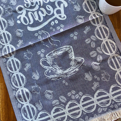 COFFEE Turkish Kitchen Towel featuring detailed coffee cup and coffee bean designs is laid out on a wooden table next to a cup of coffee