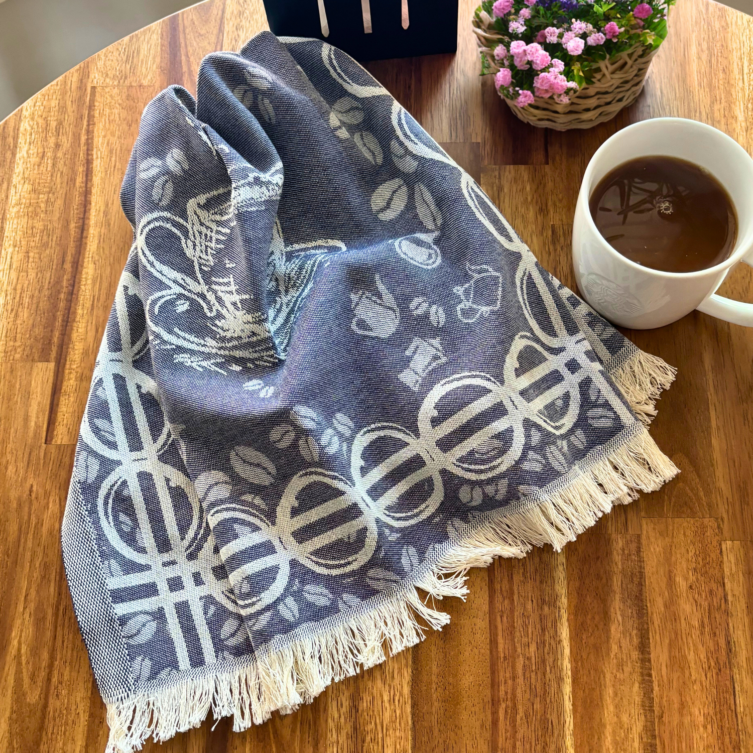 COFFEE Turkish Kitchen Towel with intricate coffee-themed patterns is draped on a wooden table next to a cup of coffee and a small flower basket