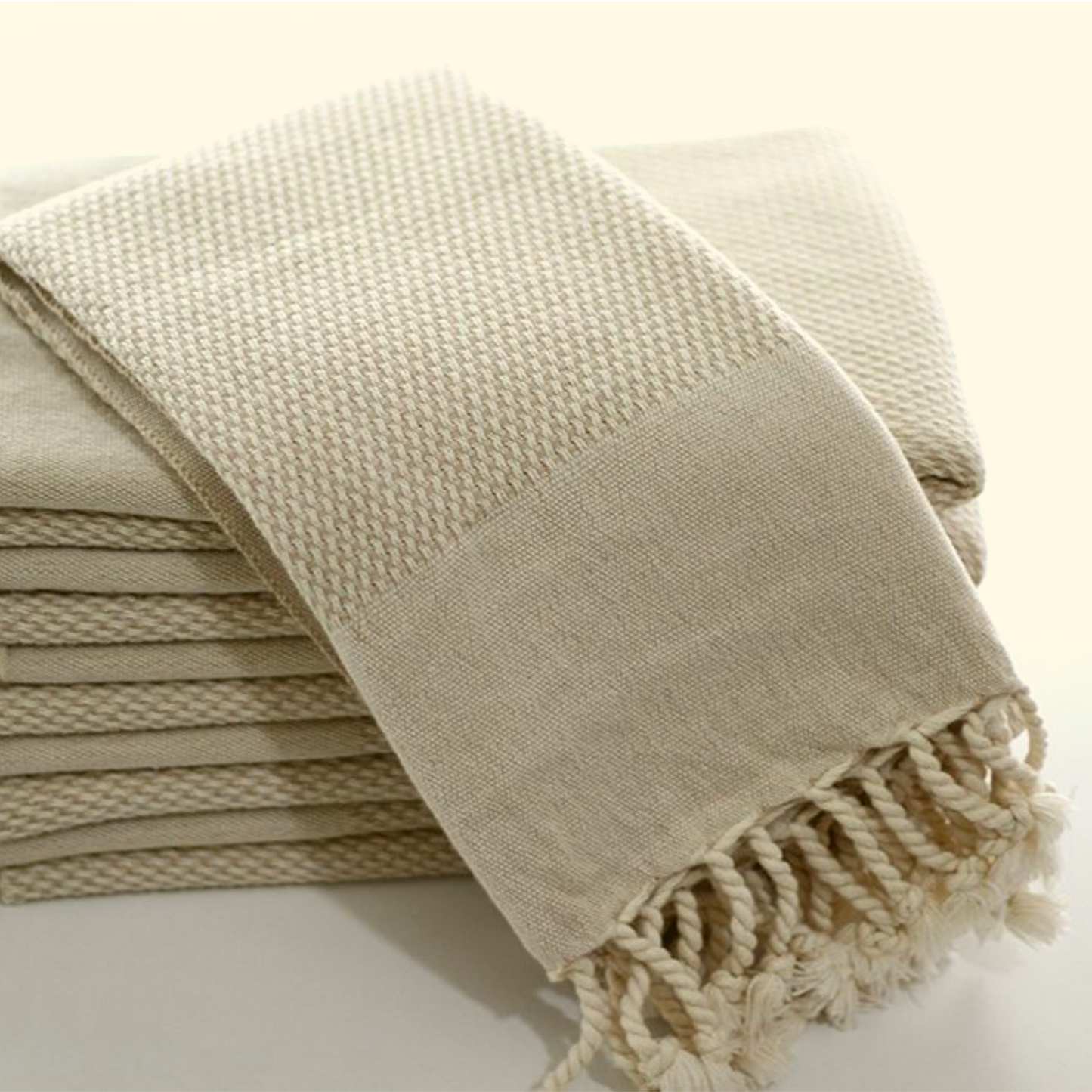 Stack of beige Turkish hand towels with intricate double-sided weaving, soft texture, and decorative fringes, ideal for bathroom or kitchen