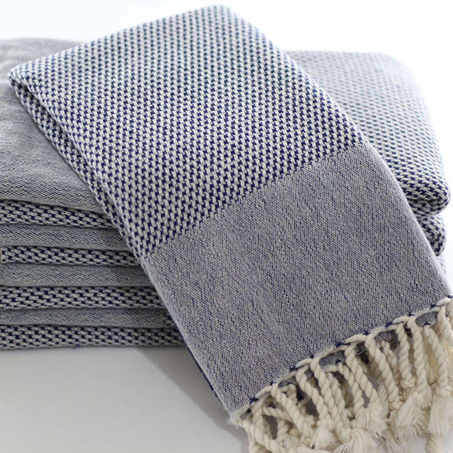 Stack of navy Turkish hand towels with soft cotton and fringes, ideal for kitchens and bathrooms.