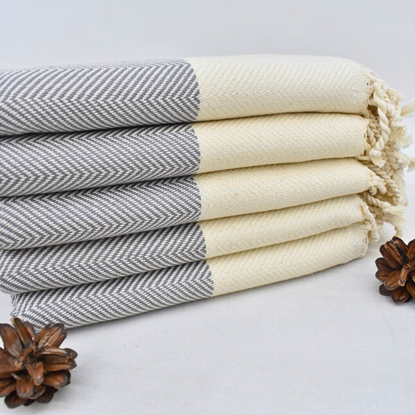 Stack of folded DOVE Turkish Hand Towels featuring a grey herringbone design and cream-coloured base, perfect for kitchens and bathrooms.