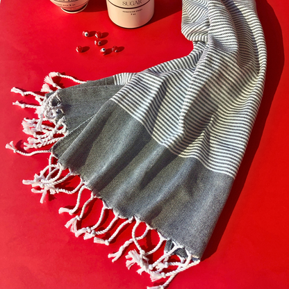 Turkish kitchen towel with black and white stripes, soft cotton material, and knotted fringes, set against a festive red background, adding style and functionality to any kitchen.