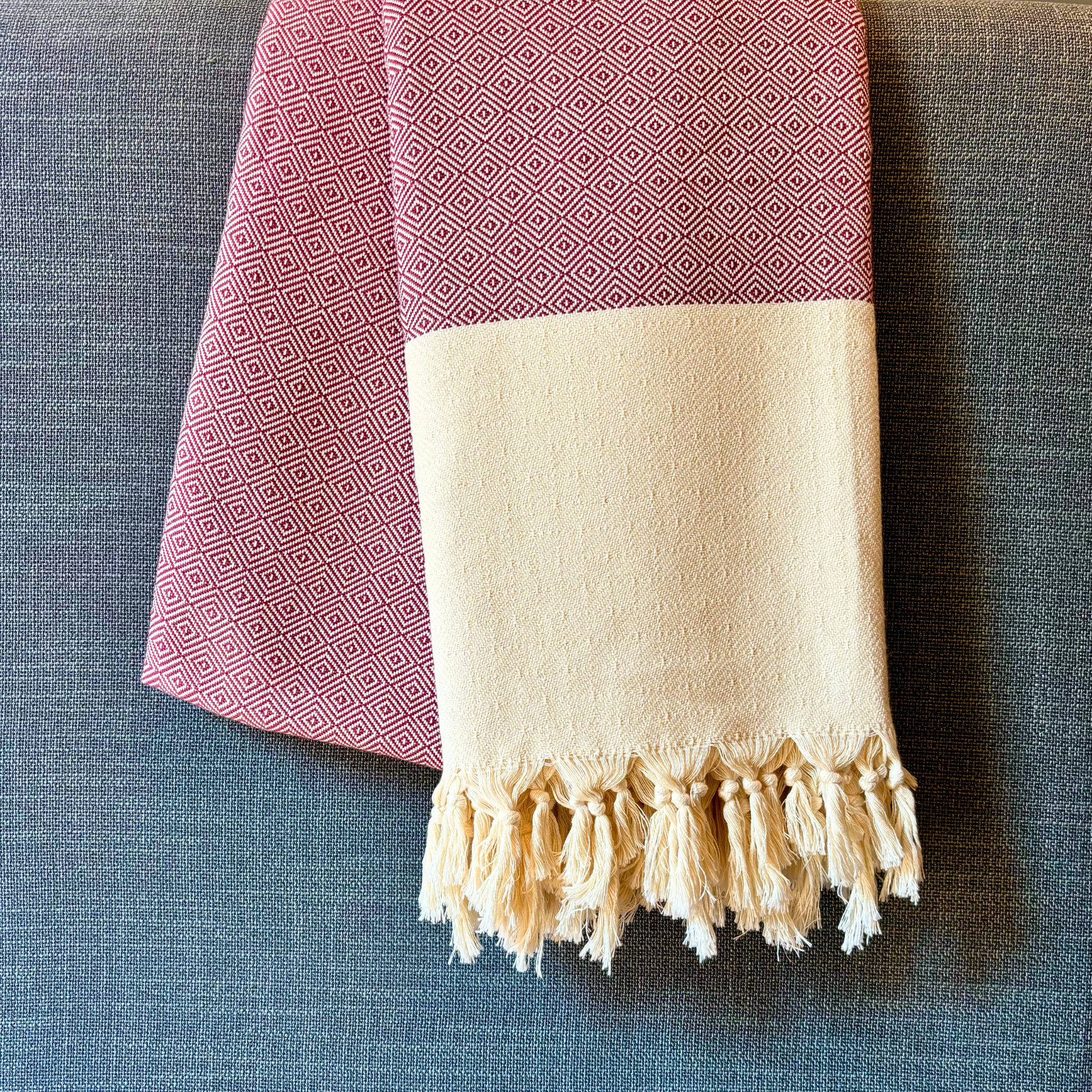 Burgundy SULTAN Bedspread with geometric diamond patterns and hand-knotted natural-coloured fringes, draped on a bed