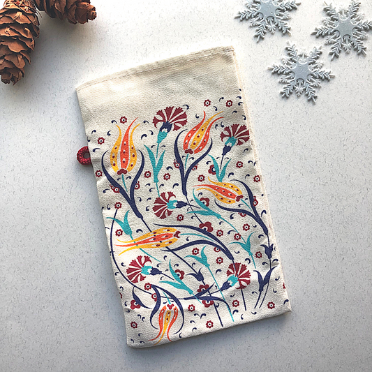 Turkish bath glove with a traditional tulip design, featuring vibrant colours and floral patterns, displayed on a festive winter background with pinecones and snowflakes